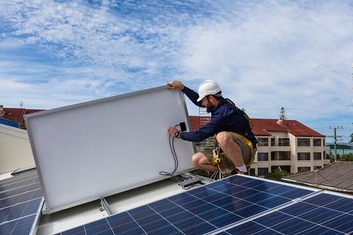 屋顶上安装太阳能电池板的人